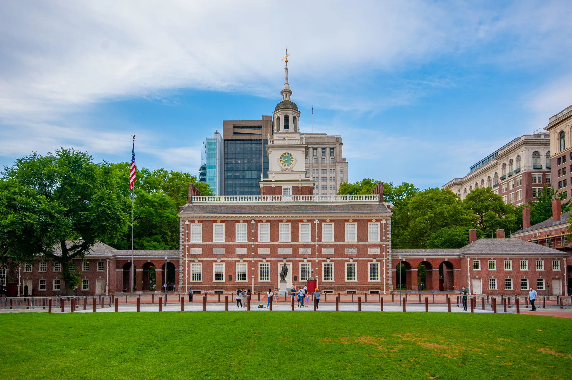 the red and white facade of independence hall building in philadelphia with tourists exploring
