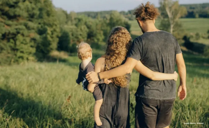 Couple walking through a grassy field with a young child