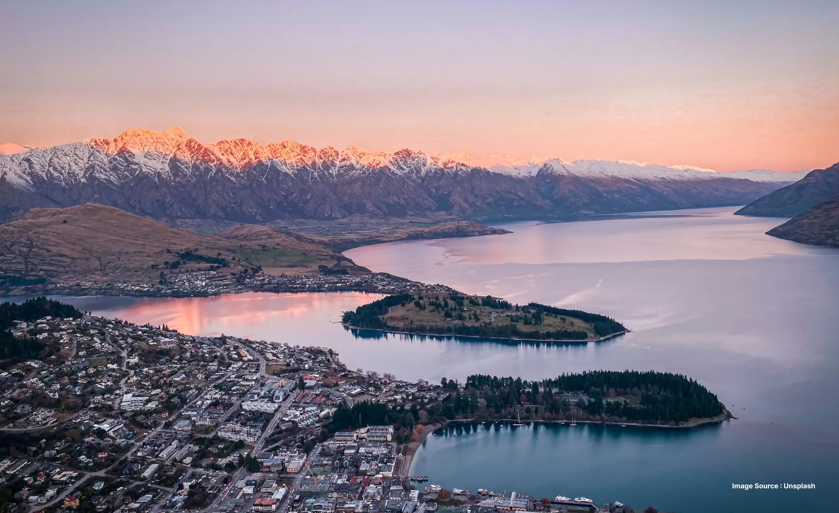 a gorgeous aerial shot of the queensland town with snow capped mountains and the populated city beneath