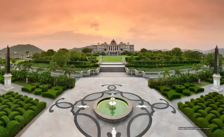 Luxury hotels in Udaipur: Grand palace hotel with lush gardens, elegant driveway, stunning sunset and royal landscape view