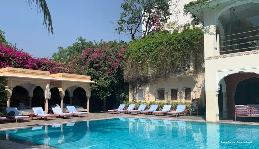 Serene outdoor swimming pool surrounded by heritage architecture and lush gardens.