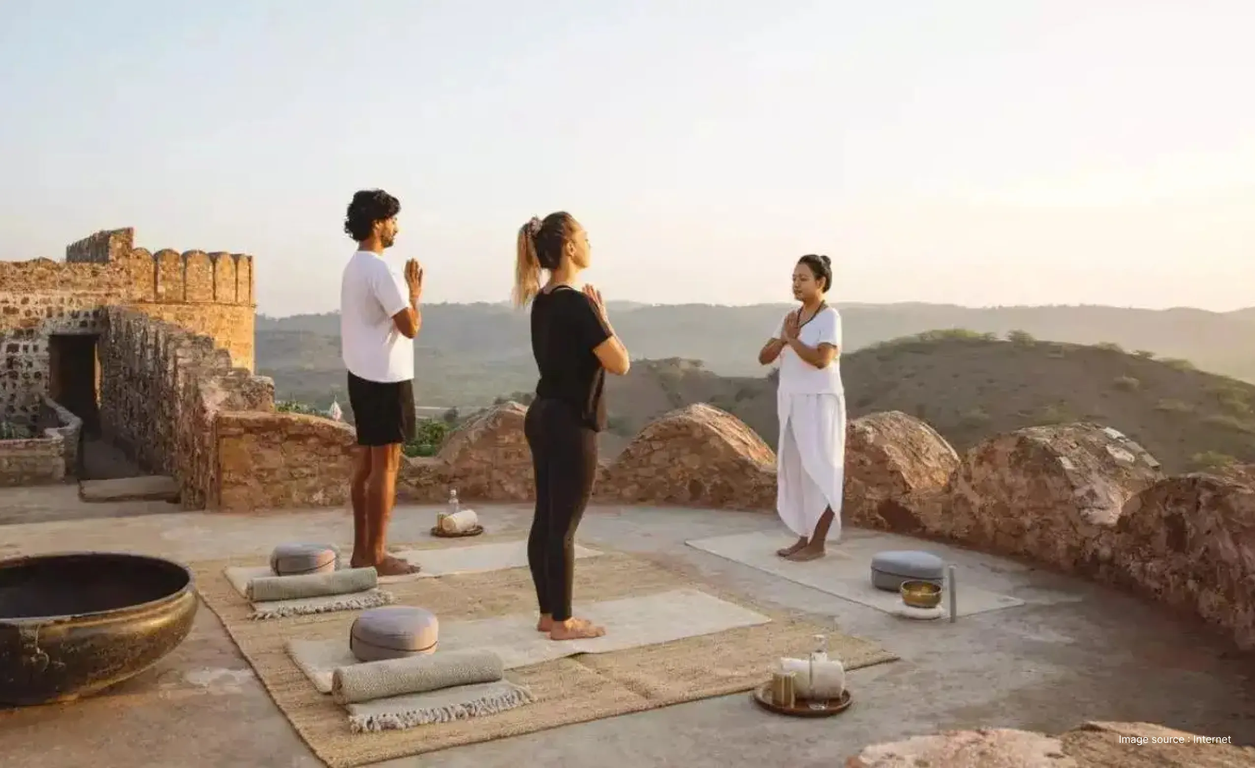 Couple Practicing Yoga with an instructor at the rooftop of a Fort in India