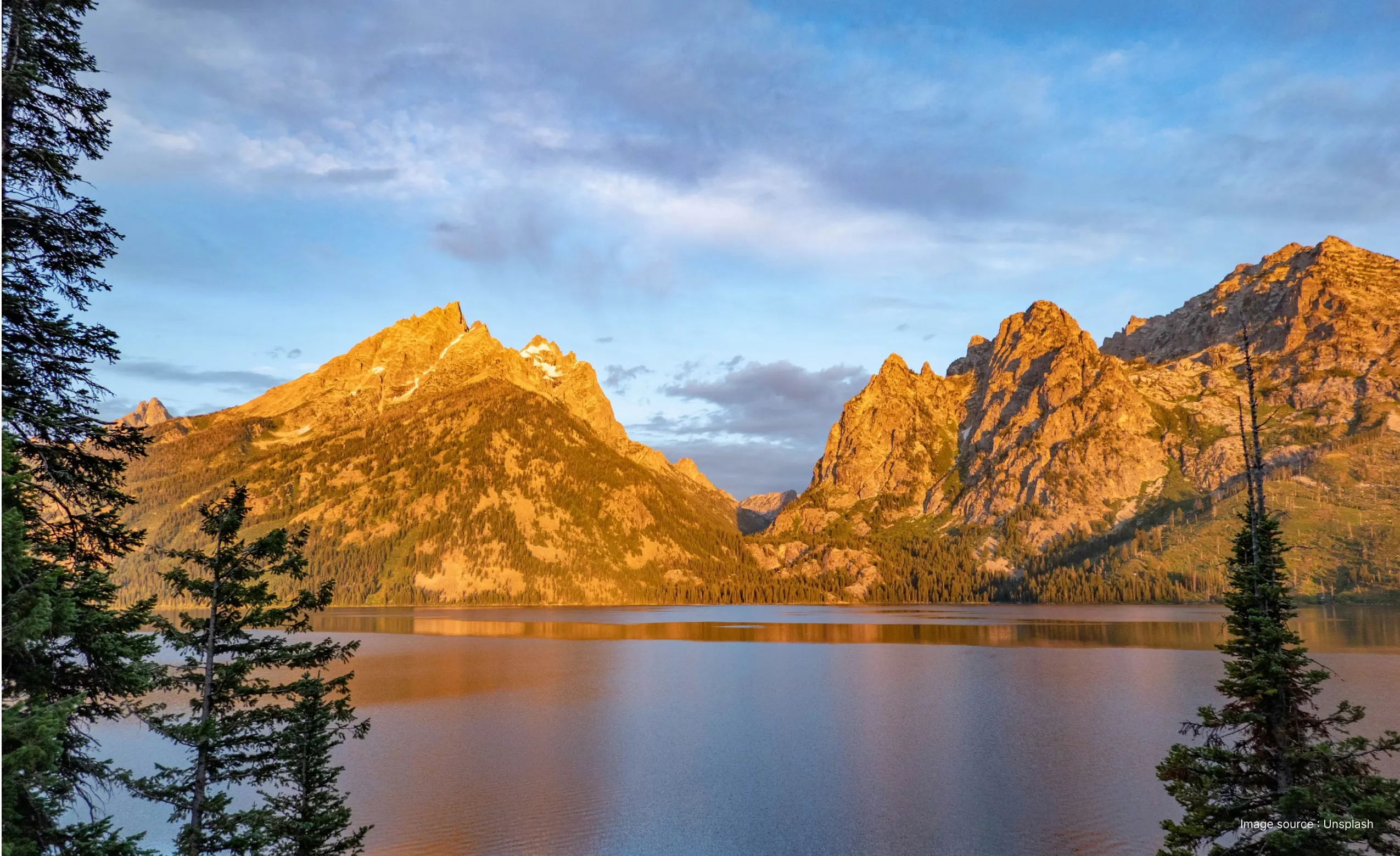a sunny day view of the tetons mountain and the jenny lake with trees in view