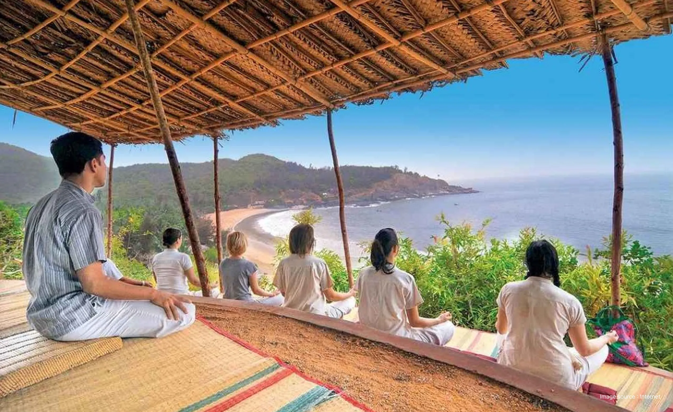 a group practicing yoga and meditation with a view of the shore