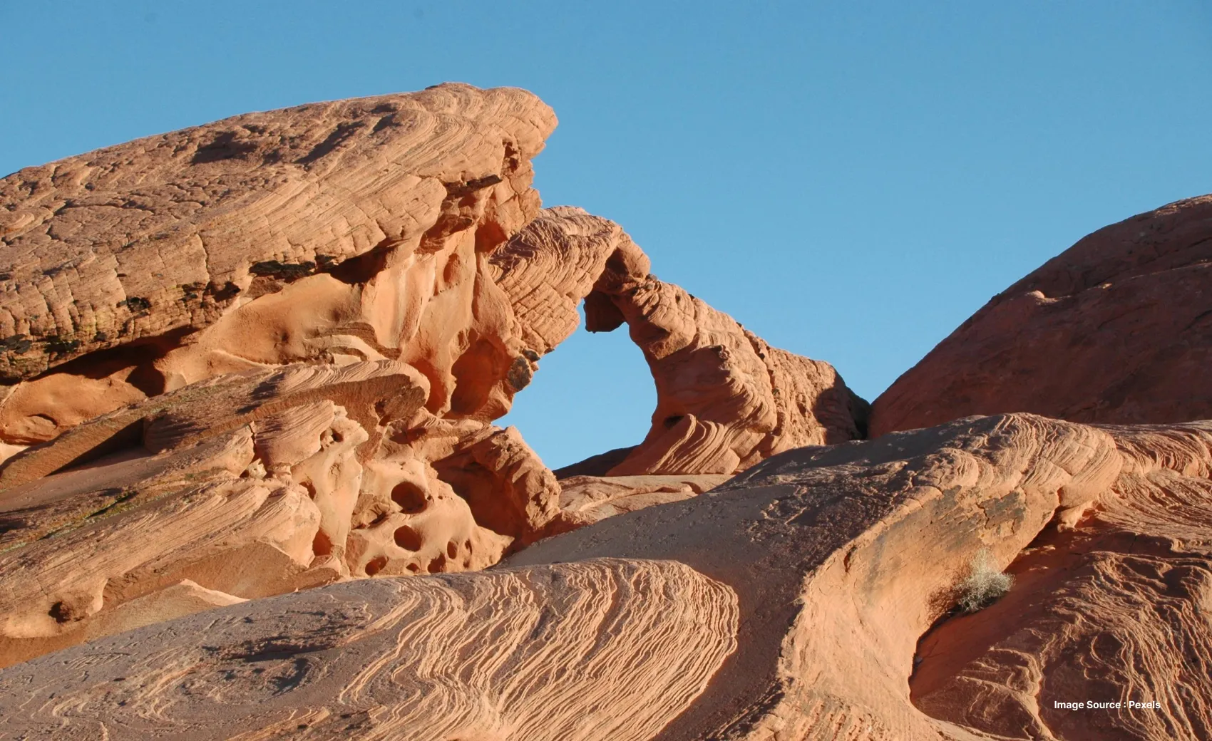 a natural rock archway wonder in the valley of fire with a clear blue sky