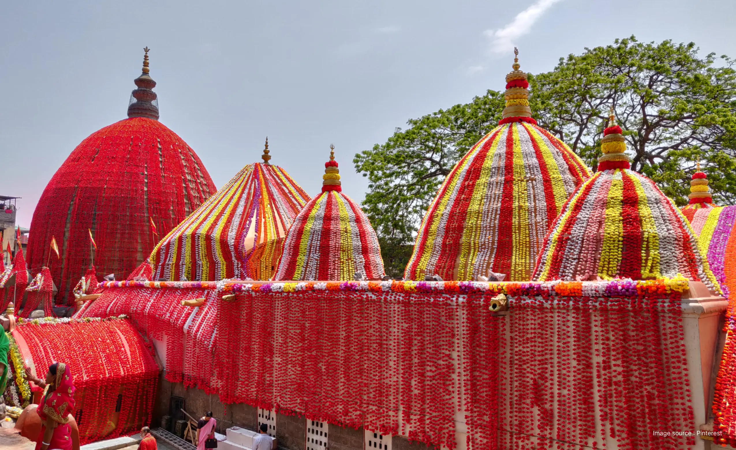 the kamakhya temple in assam, with all its spires and domes decorated in many red flowers