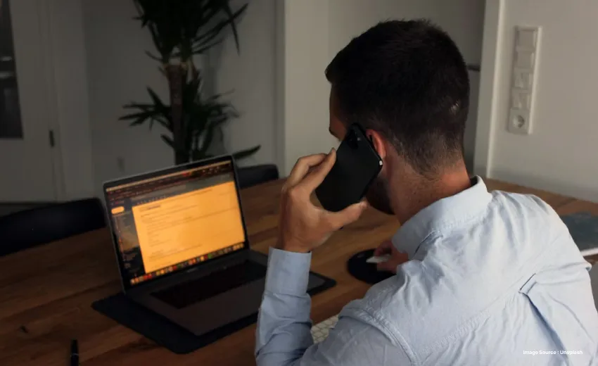 Someone on call whilst looking at a laptop