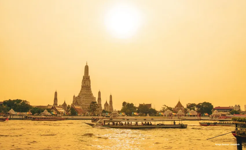 Historic riverside temple complex rising above boats on a tranquil waterway.