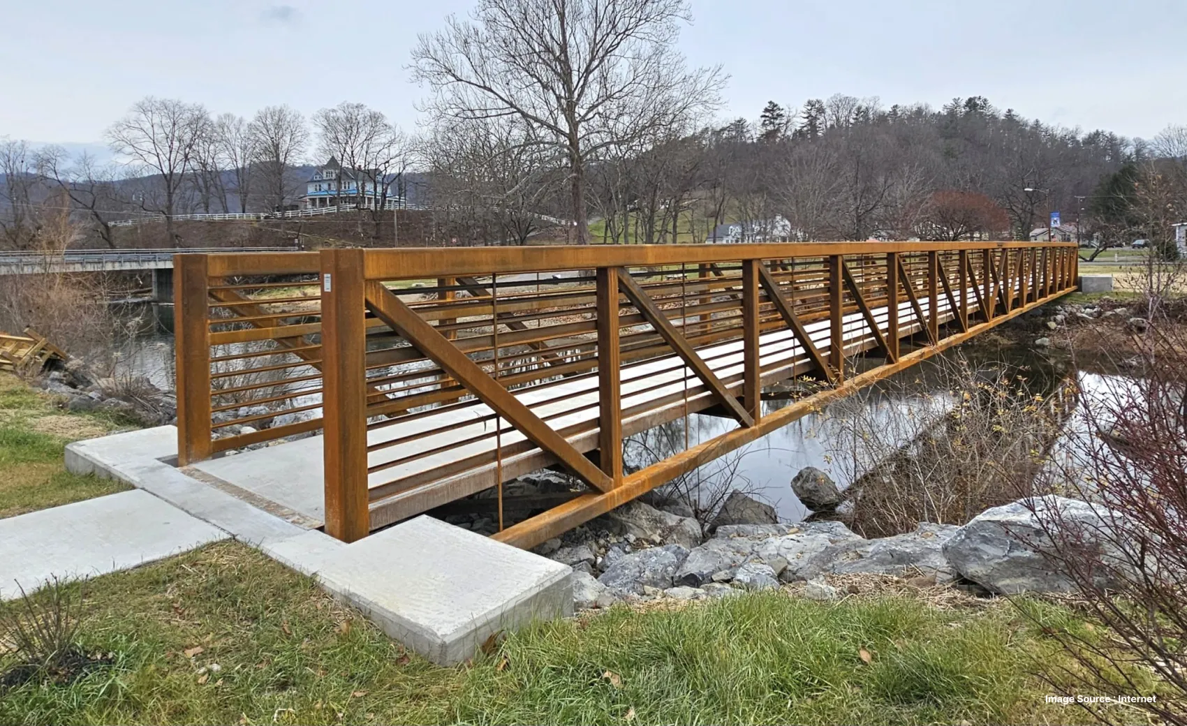 spread creek bridge with wooden fencing and leafless trees