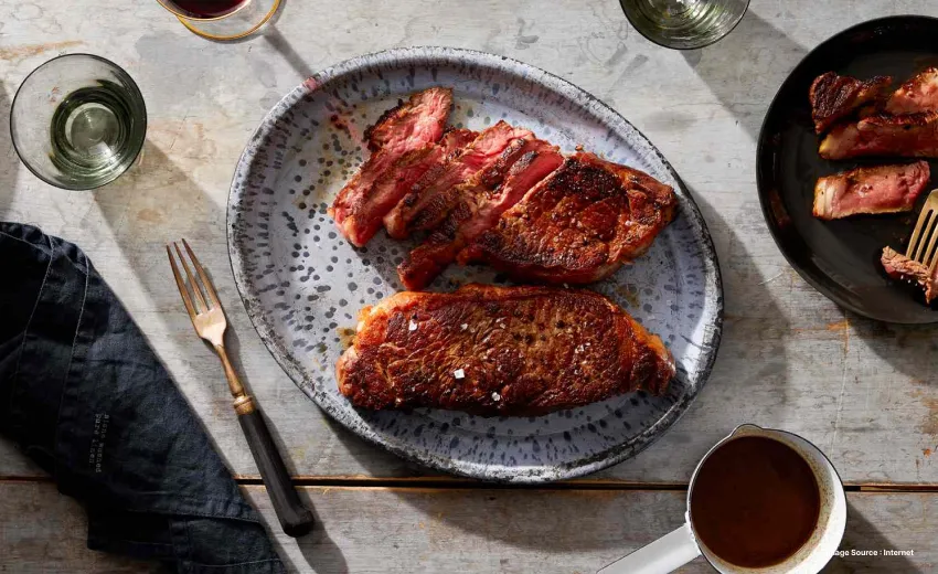A gourmet looking steak served on a beautiful platter with cutlery