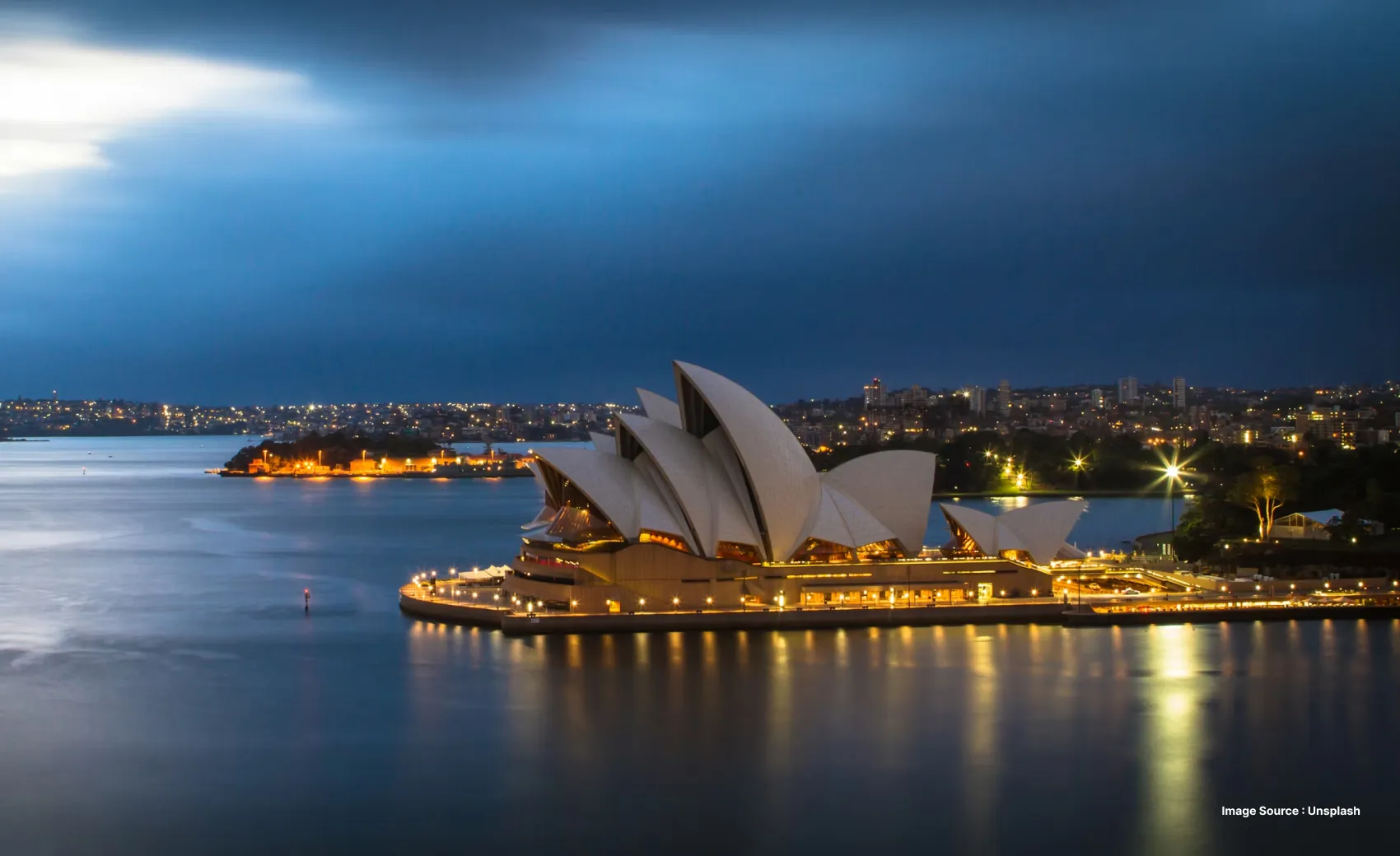 an evening view of the iconic opera house lit up with the city's skyline in view
