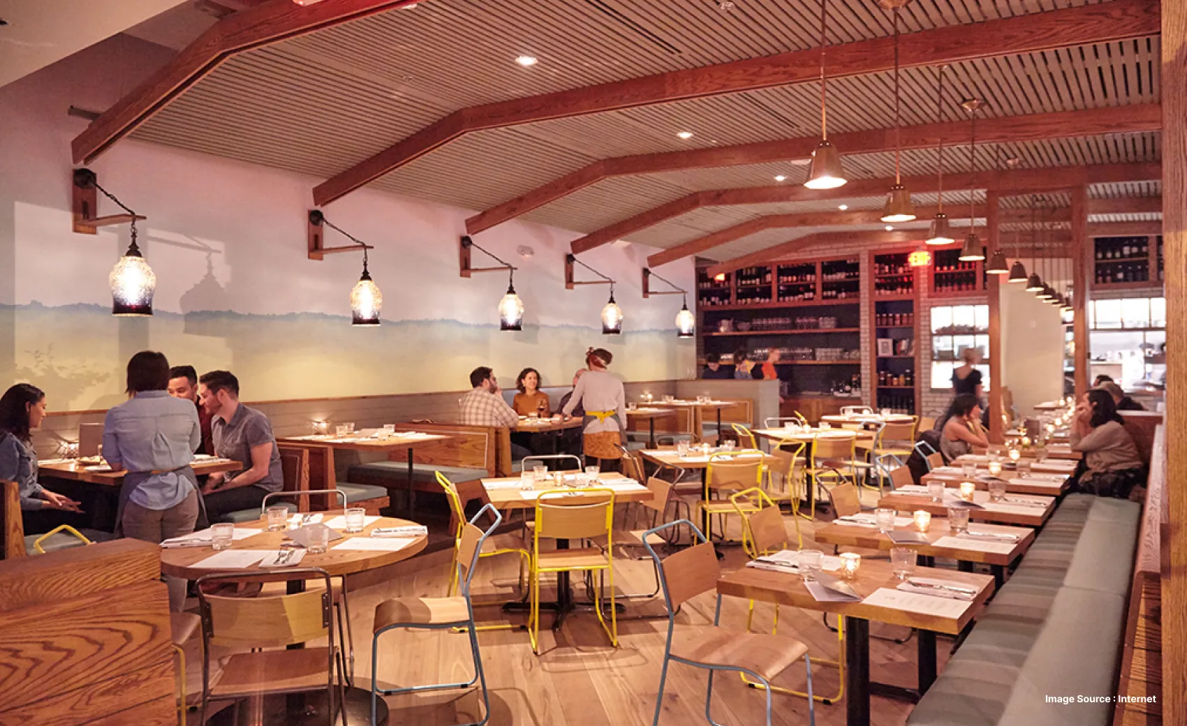 a lively restaurant with waitresses tending to tables with wooden furniture