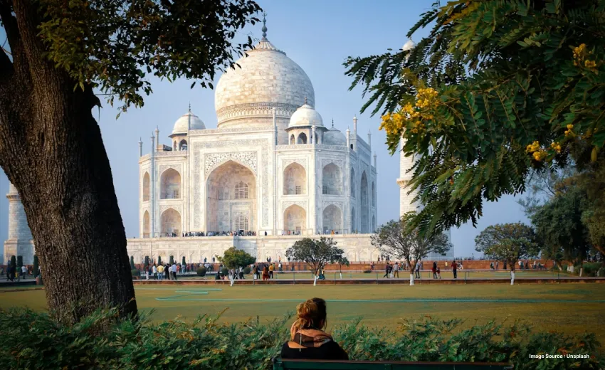 a shot of the taj mahal from its gardens during the day as tourists explore