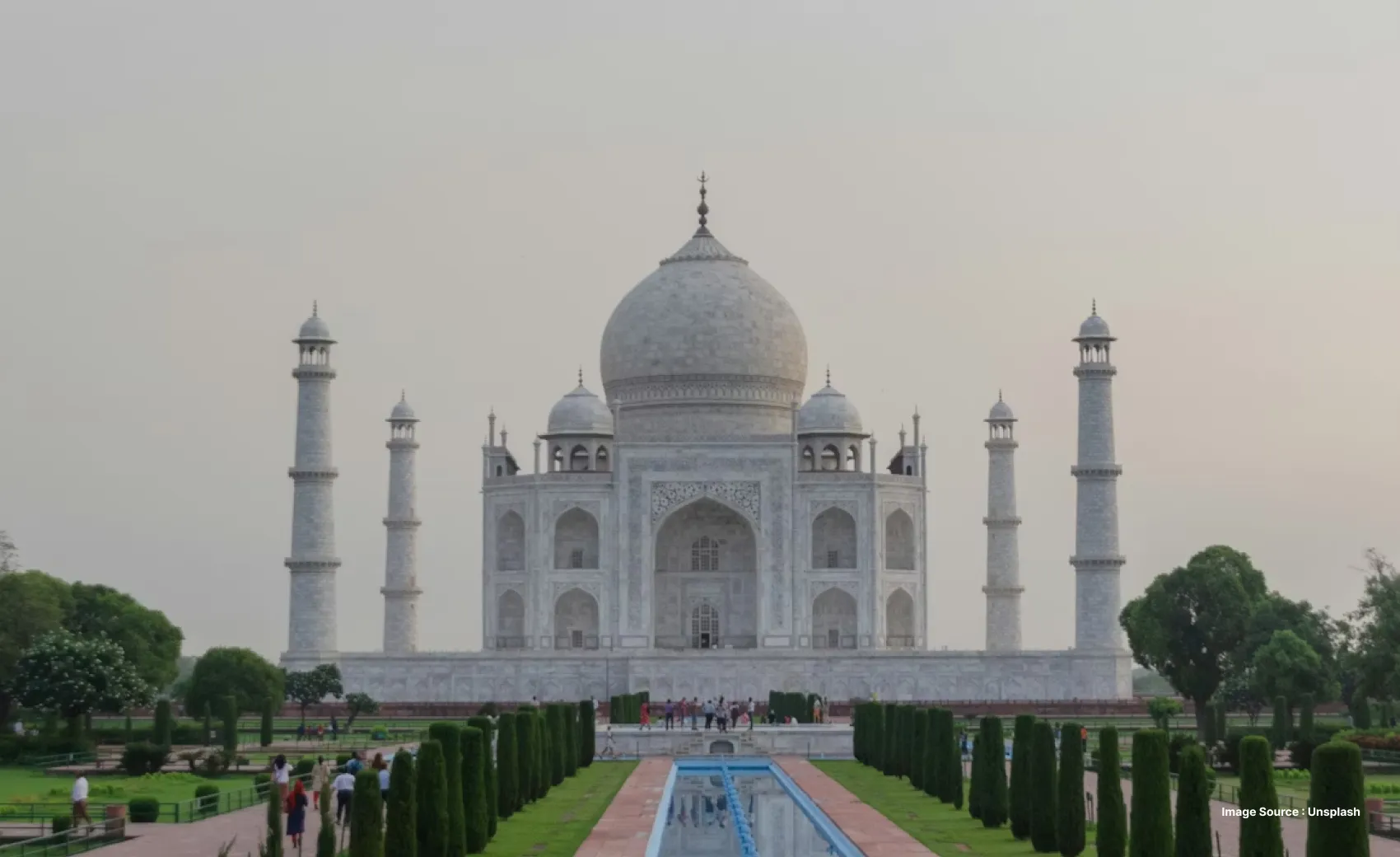 a daytime view of the taj mahal from the front as tourists walk ahead