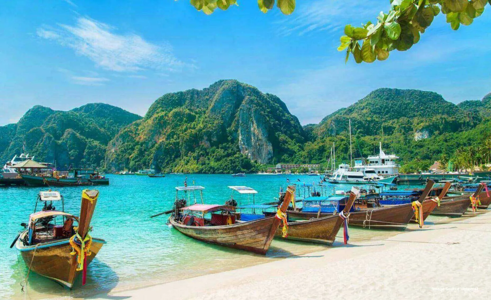 A bunch of wooden boats parked on the shore at a beach with green Hill in the back