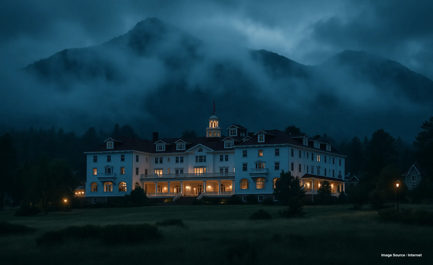 a haunting view of the stanley hotel at night with dense clouds in the sky and lit up rooms
