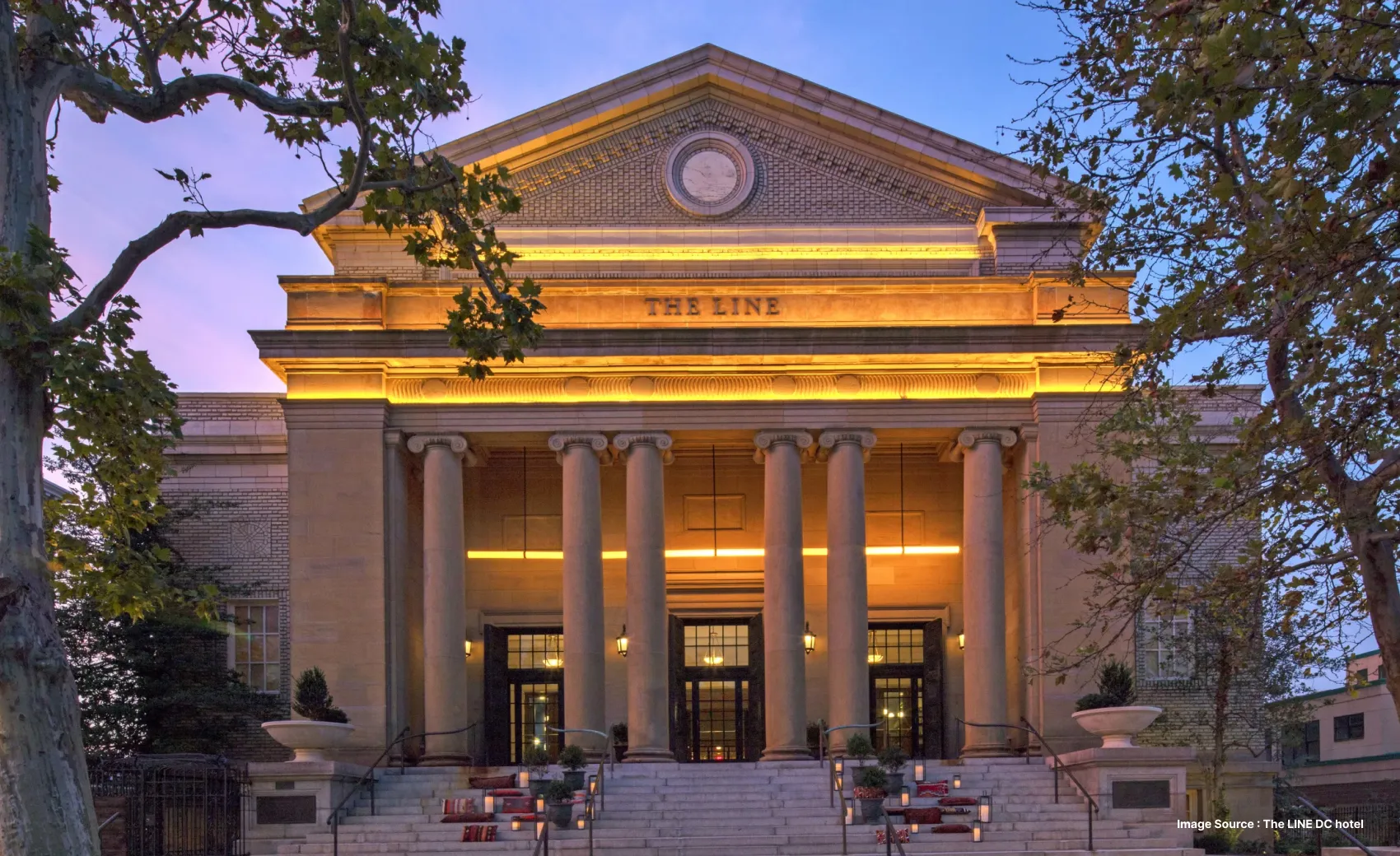 the line dc hotel lit up in golden lights with pillars at its entrance at dush