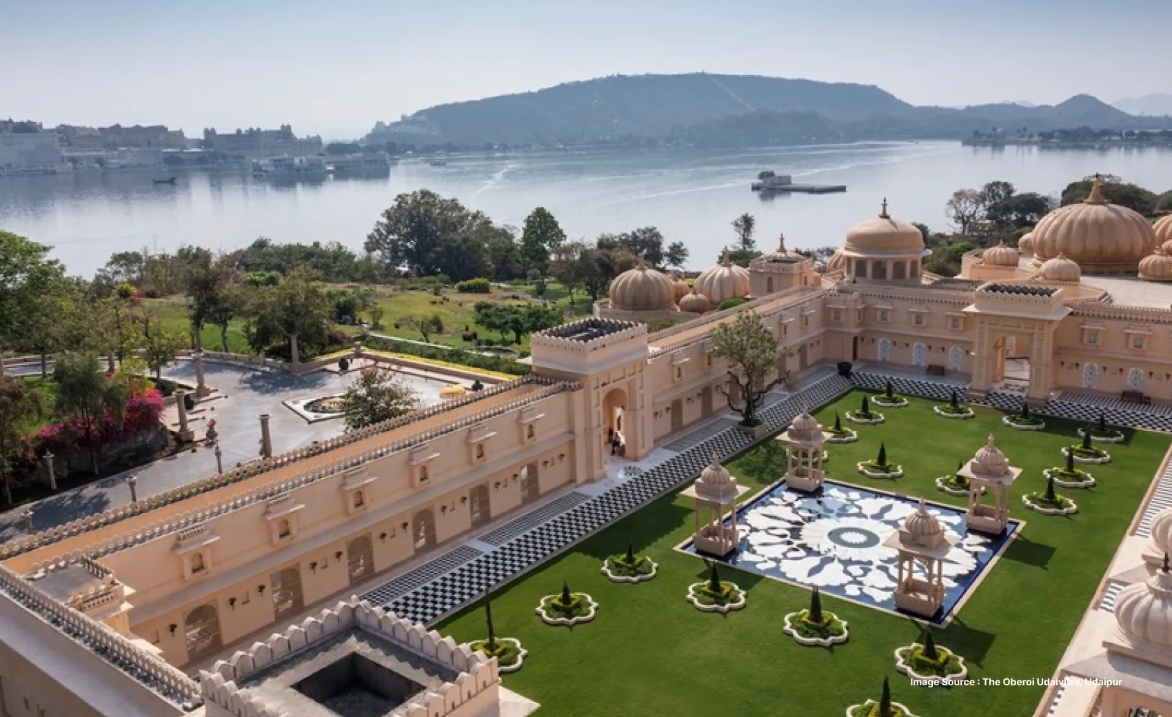 a serene view of one of the ornate courtyards of the oberoi udaivilas with the lake pichola in frame