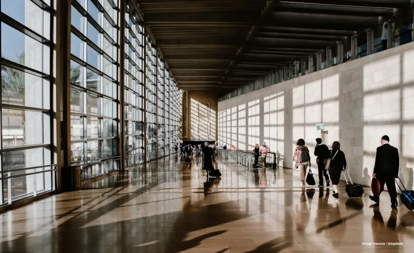 capture of an airport during afternoon as travelers walk ahead with suitcases
