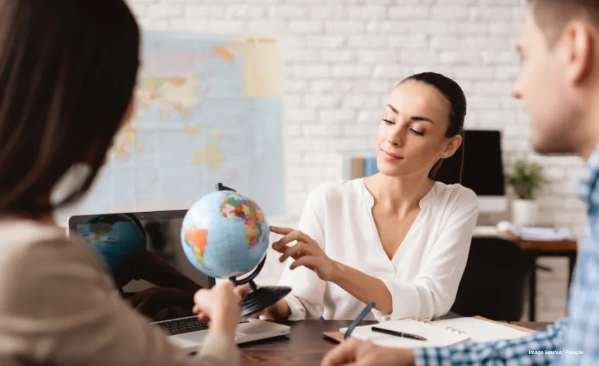 a lady pointing to a globe as she talks to two people