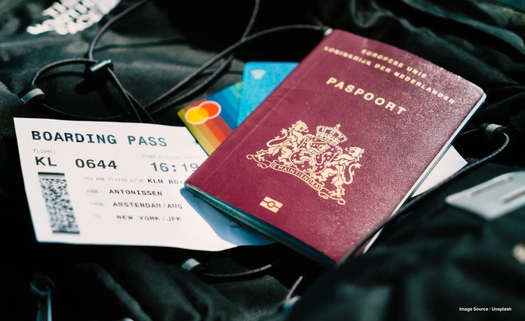 travel documents lying on top of a black bag like passport boarding pass and credit cards