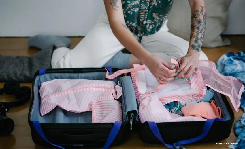 Traveler packing clothes efficiently into a suitcase before departure