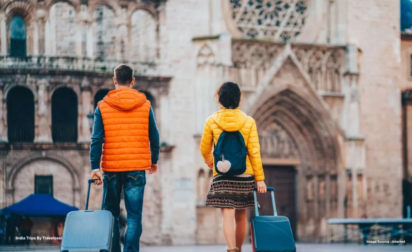 a picture of two people walking two a heritage building whilst strolling two suitcases