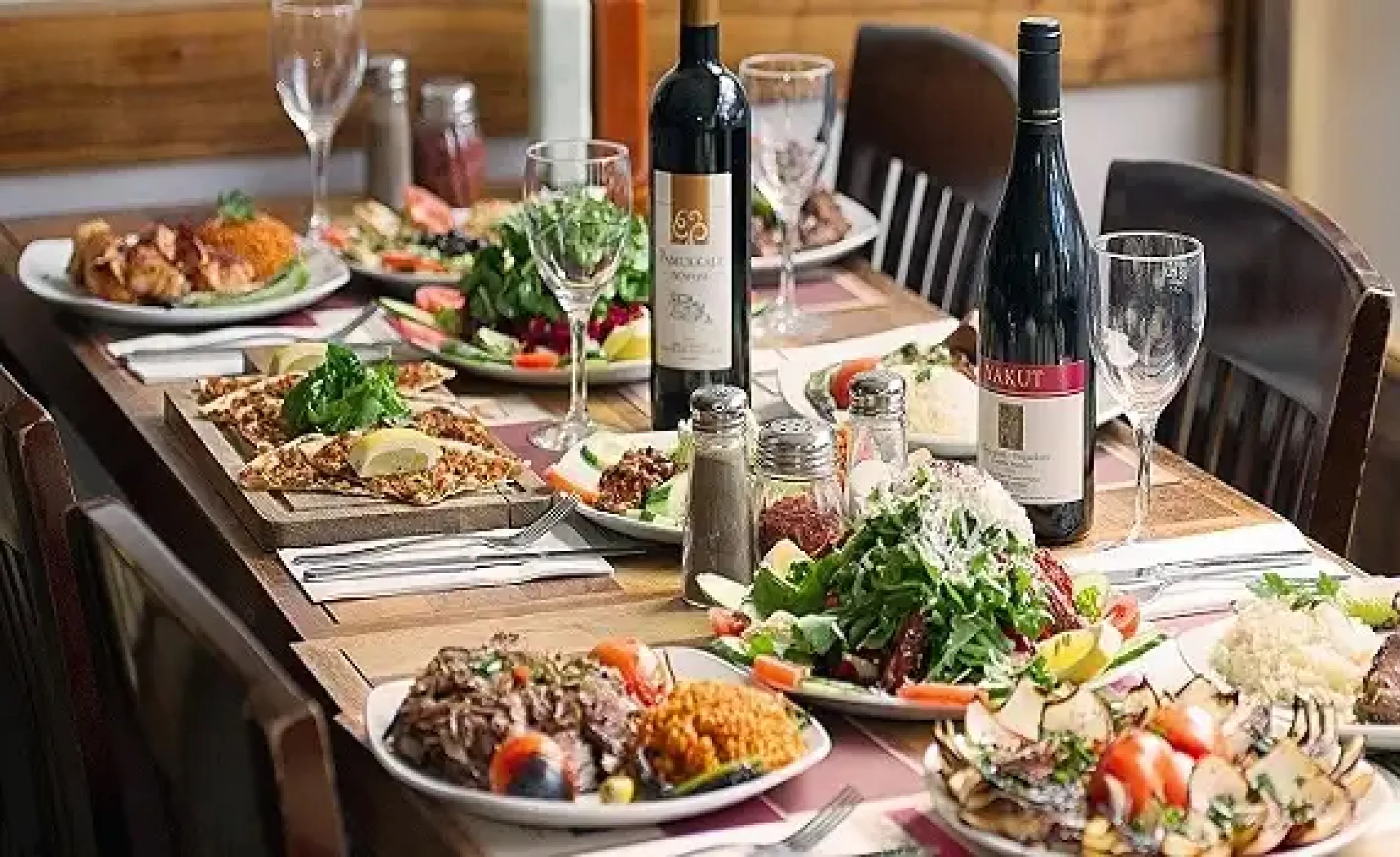 a fine dining set up with turkish food and bottles of wine with kebabs and fresh salads