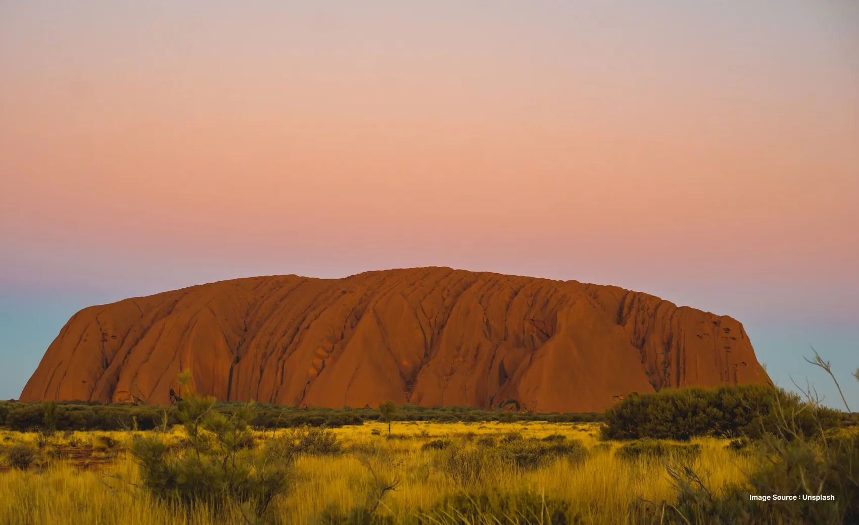 sunset view of the huge red sandstone rock structure in uluru