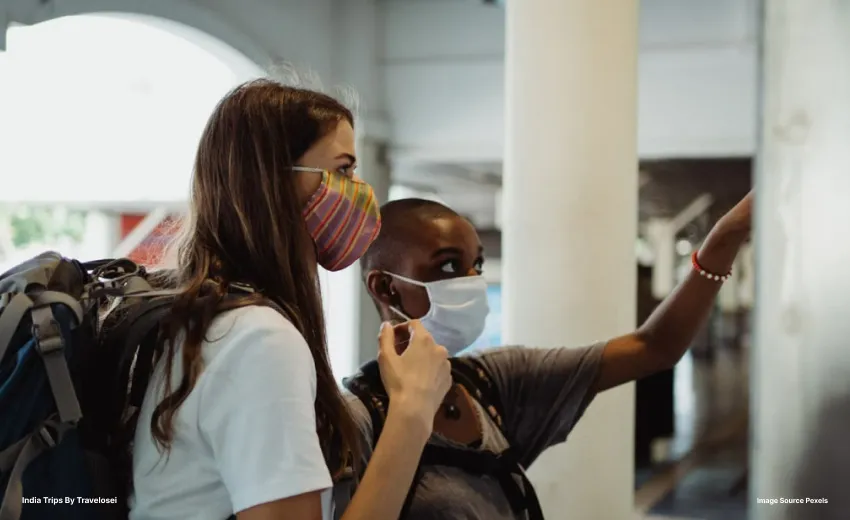 two women in masks pointing at a wall