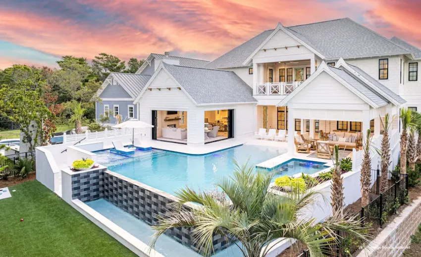 A beautiful private white resort with multiple bedrooms and a pool during sunset, surrounded by greenery