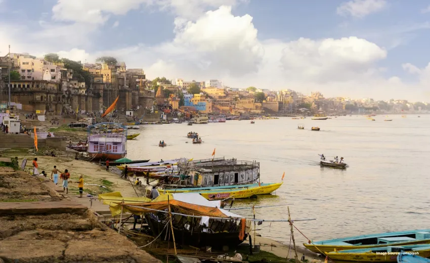 a lively shot of the riverbanks at varanasi with boats and lined up houses