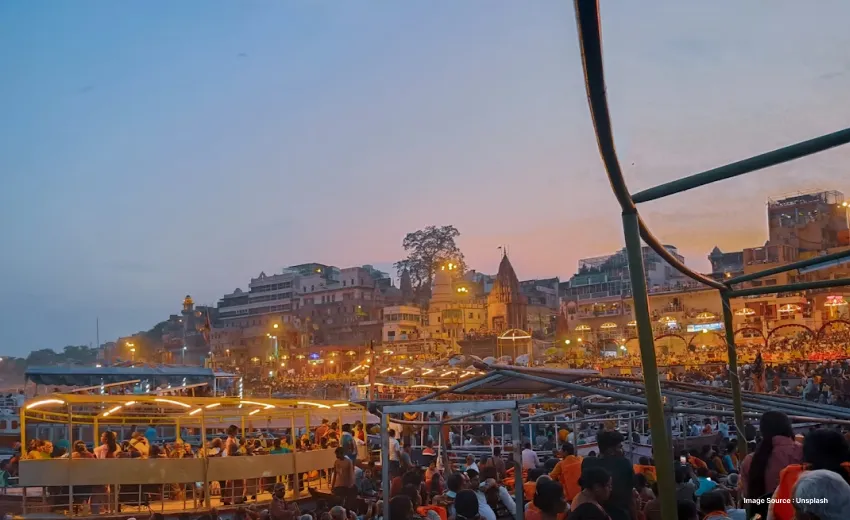a colorful view of varanasi from its riverbank as a boat with tourists passes by and temples on land