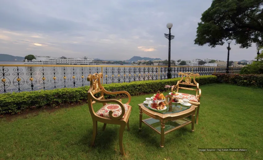 Luxury hotels in Udaipur: Elegant garden seating with lake view, royal chairs and table set for tea by the water