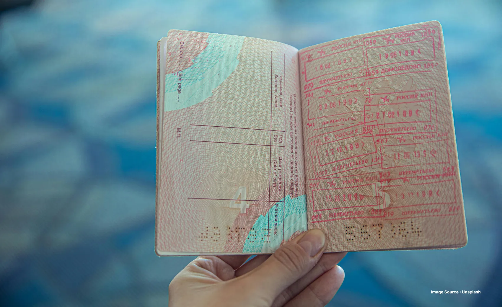 an orange visa stamped on a passport as a person holds it open