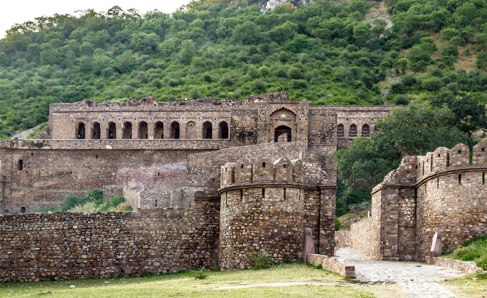 an ancient looking fort in rajasthan with green hilltop and corridors lined with small windows
