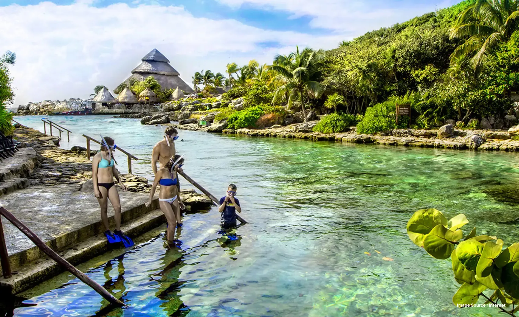 a family wearing snorkelling gear walking into the pool surrounded by lush greenery
