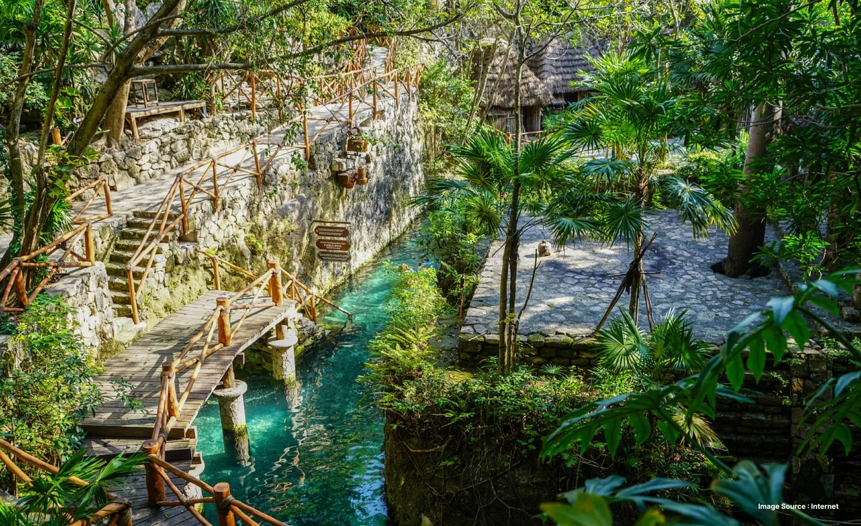 inside the xcaret park with an overbridge by a pool with green trees