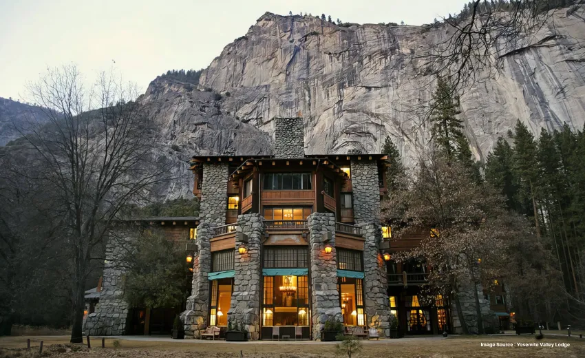 front view of the yosemite valley lodge with lit up rooms inside, in front of a large rocky cliff