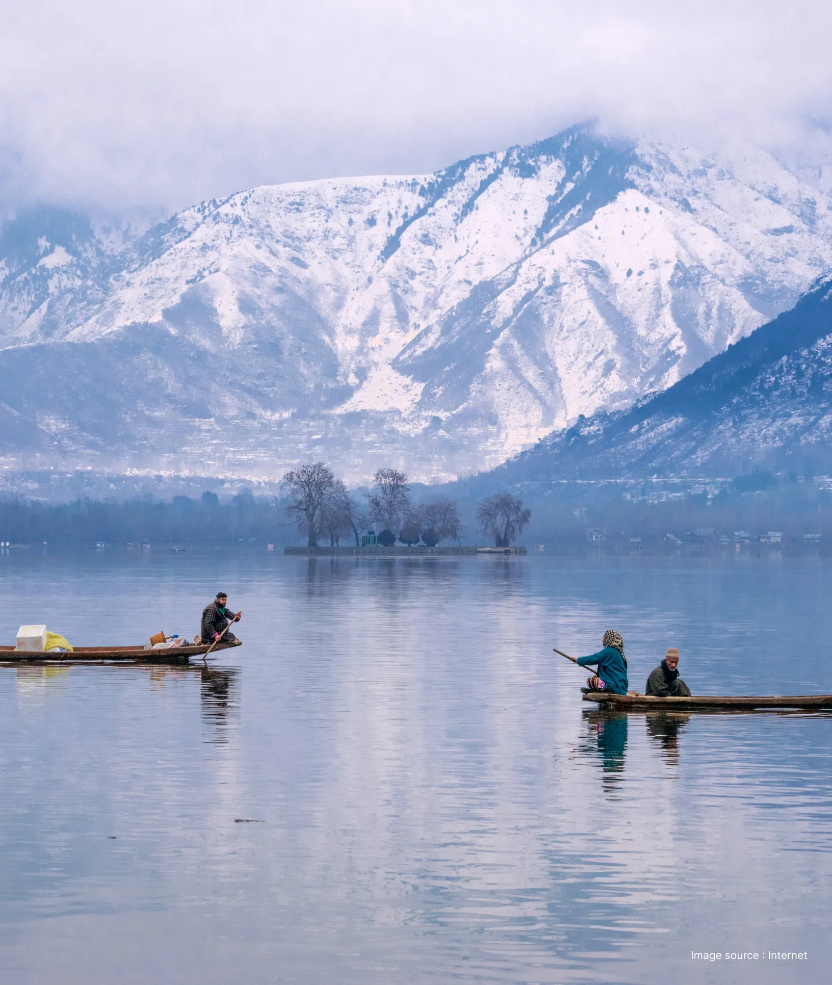 two shikara boats cruise on the dal lake with the snow capped himalayas in the background