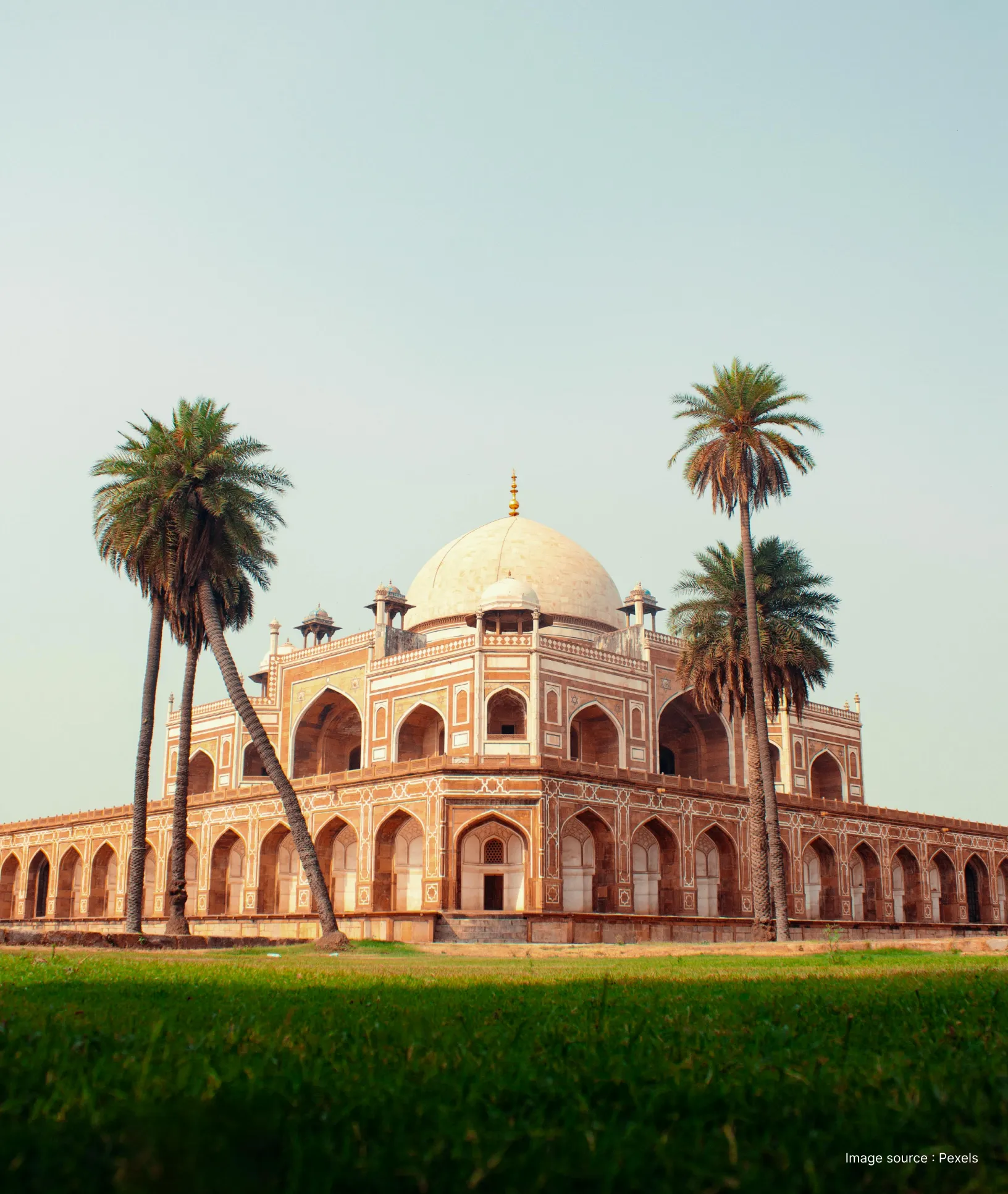 side view of the humayuns tomb in delhi flanked by a few palm trees and an expansive garden