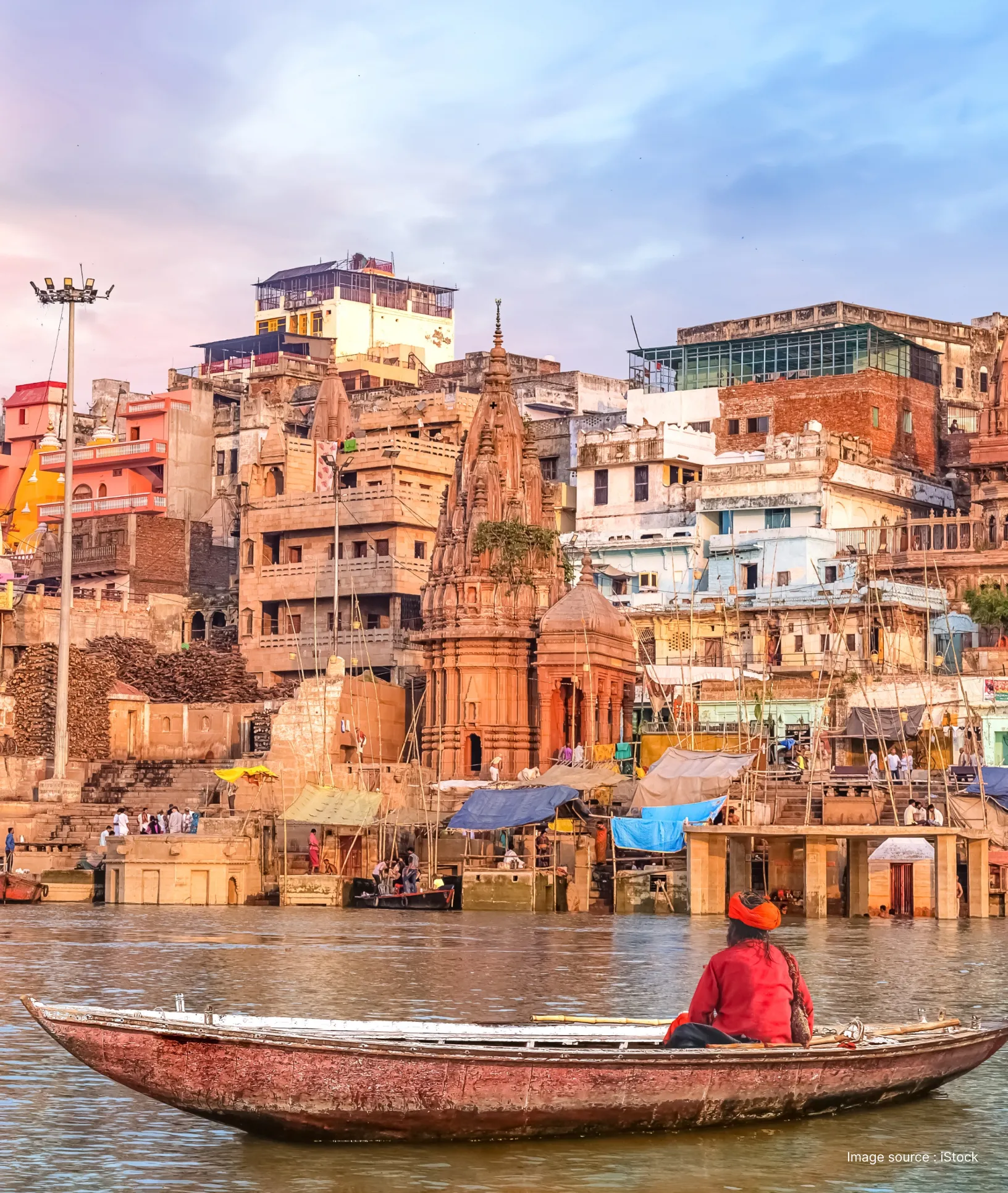 a man in a boat in the ganges river in front of a riverbank in varanasi