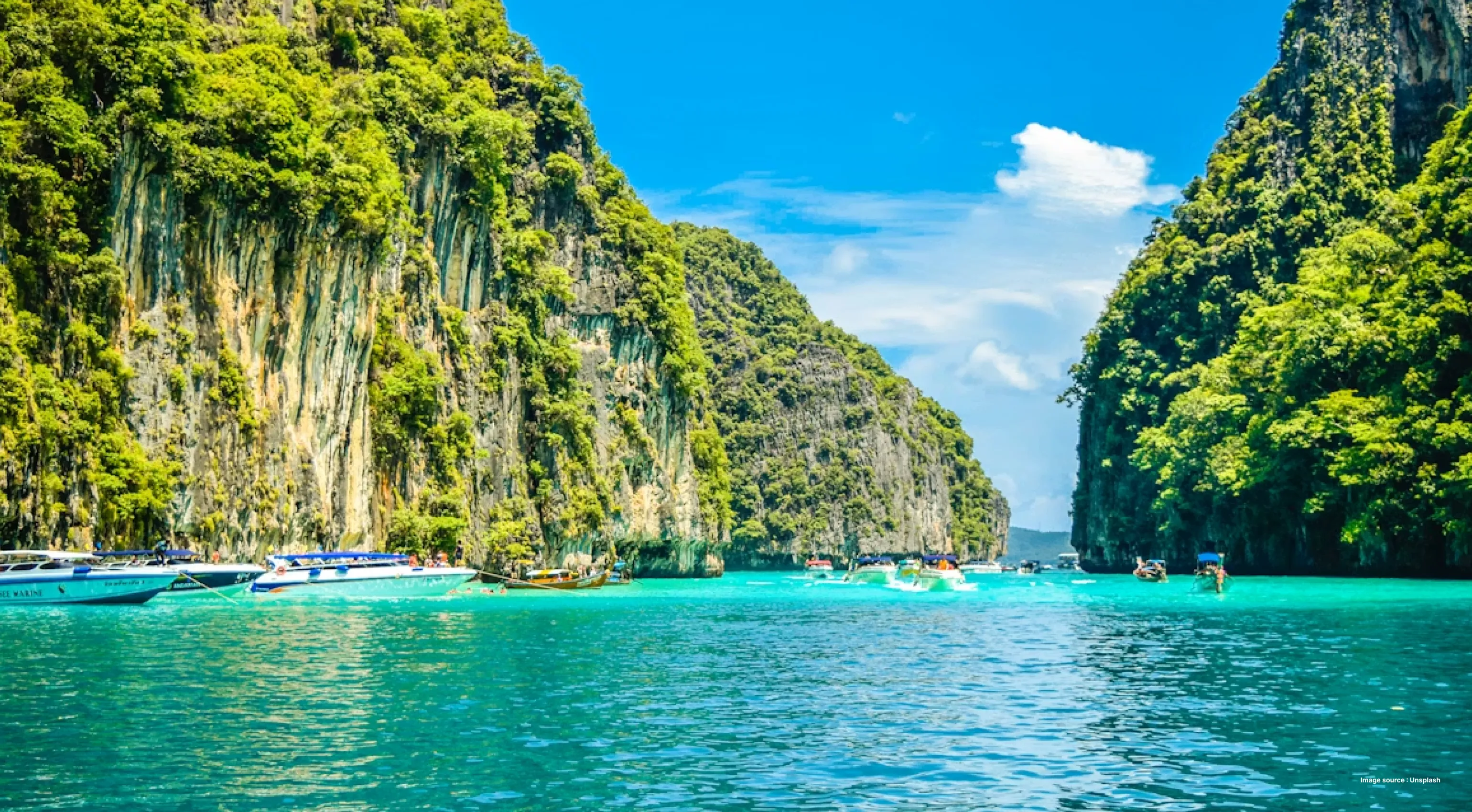 lush green cliffs on the andaman island with yachts and tourists boat in the water
