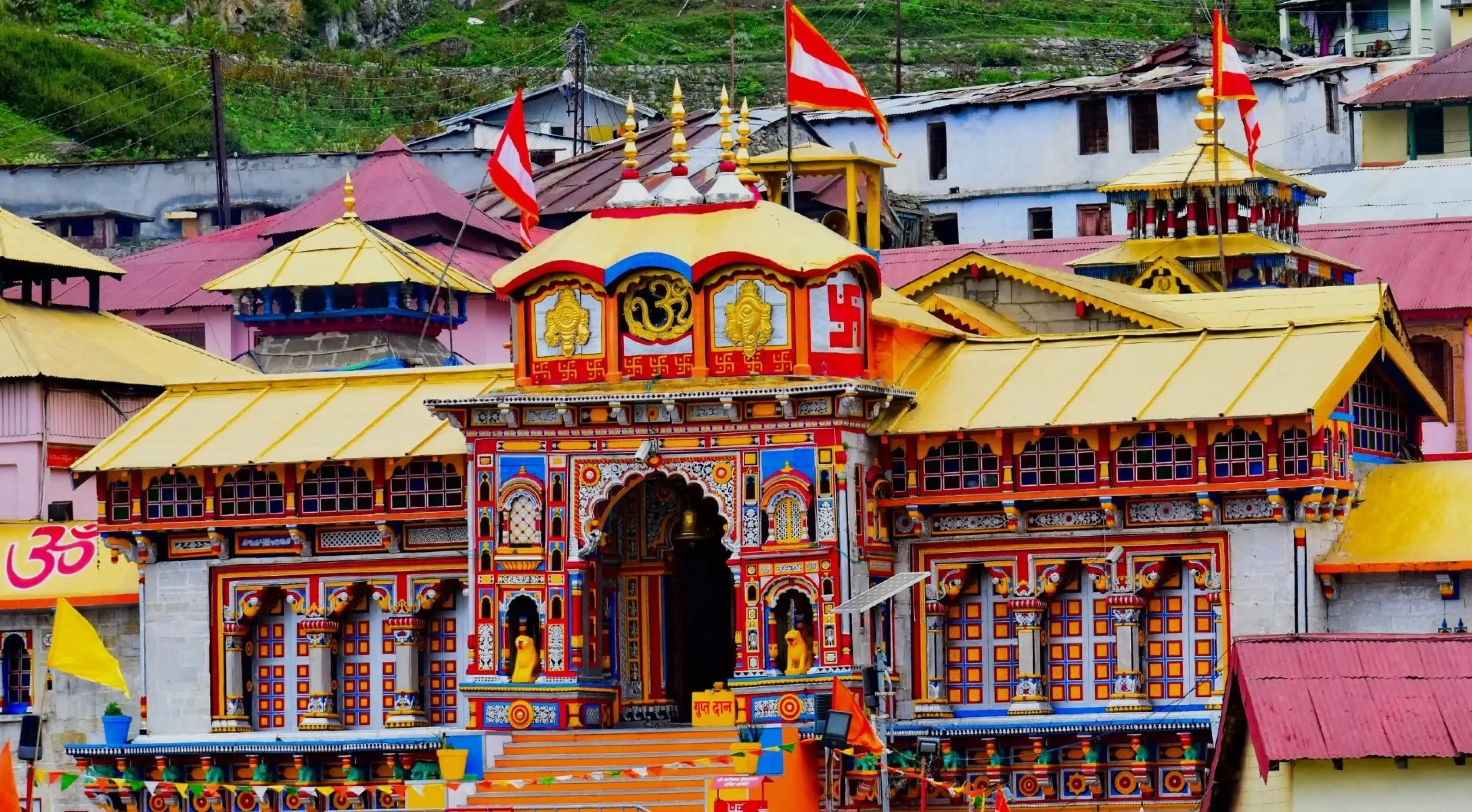 Badrinath Temple in Uttarakhand showcasing its vibrant multicolored façade, ornate entrance, and sacred Hindu symbols against the Himalayan town backdrop
