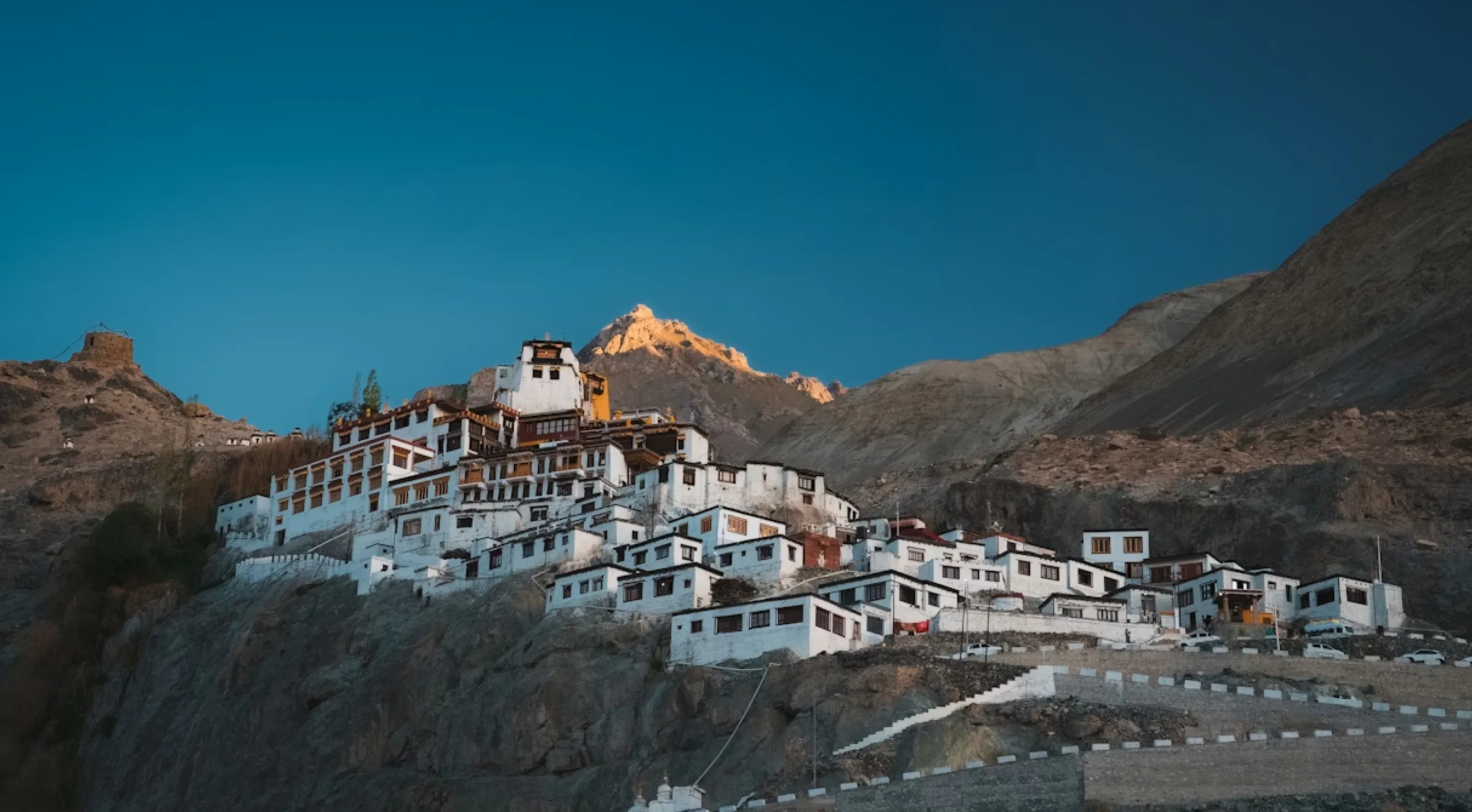 a group of white buildings on a dry rugged valley in hemis