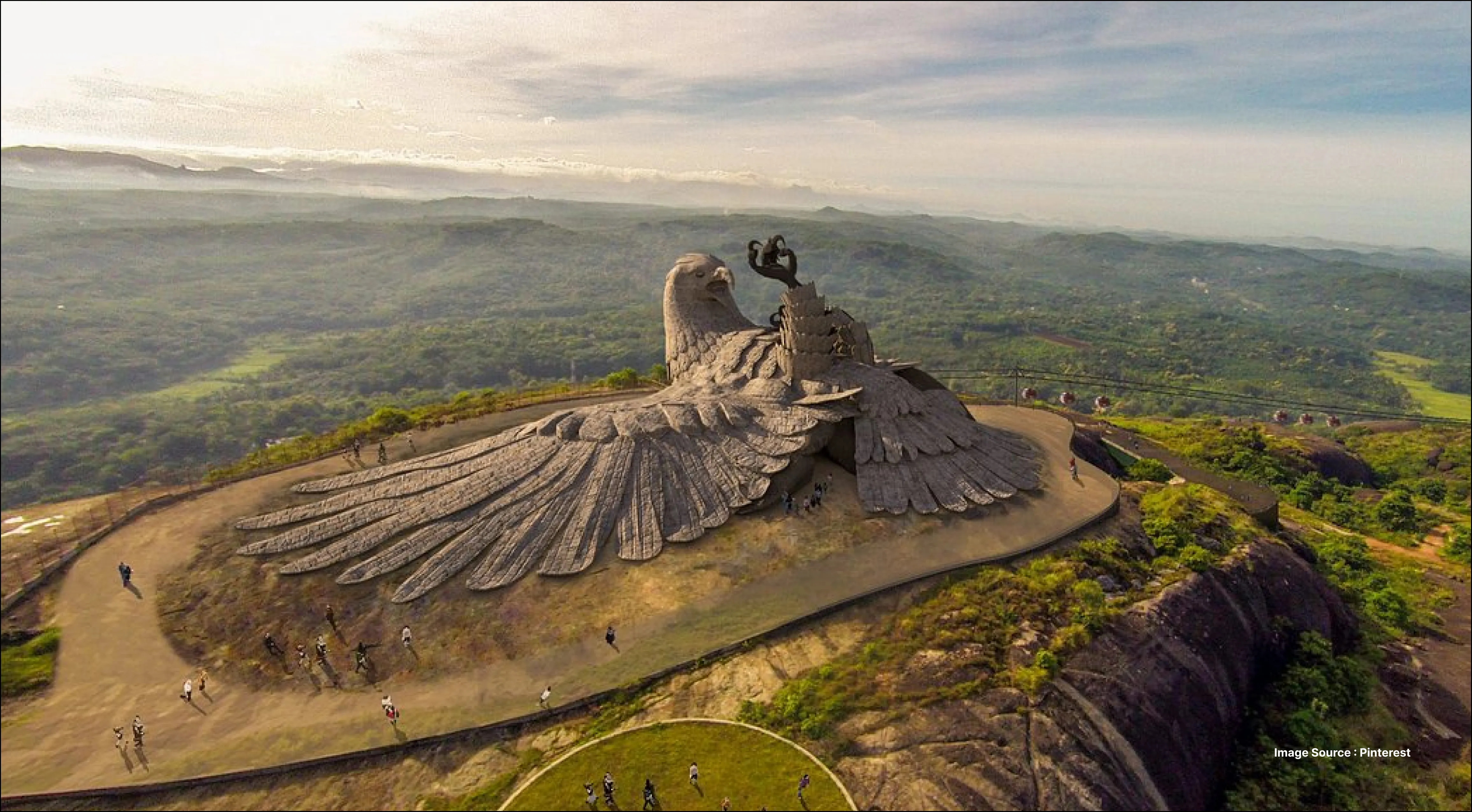 an aerial shot of the incredible statue of jatayu (an eagle mythological character) in india with mountains surrounding it
