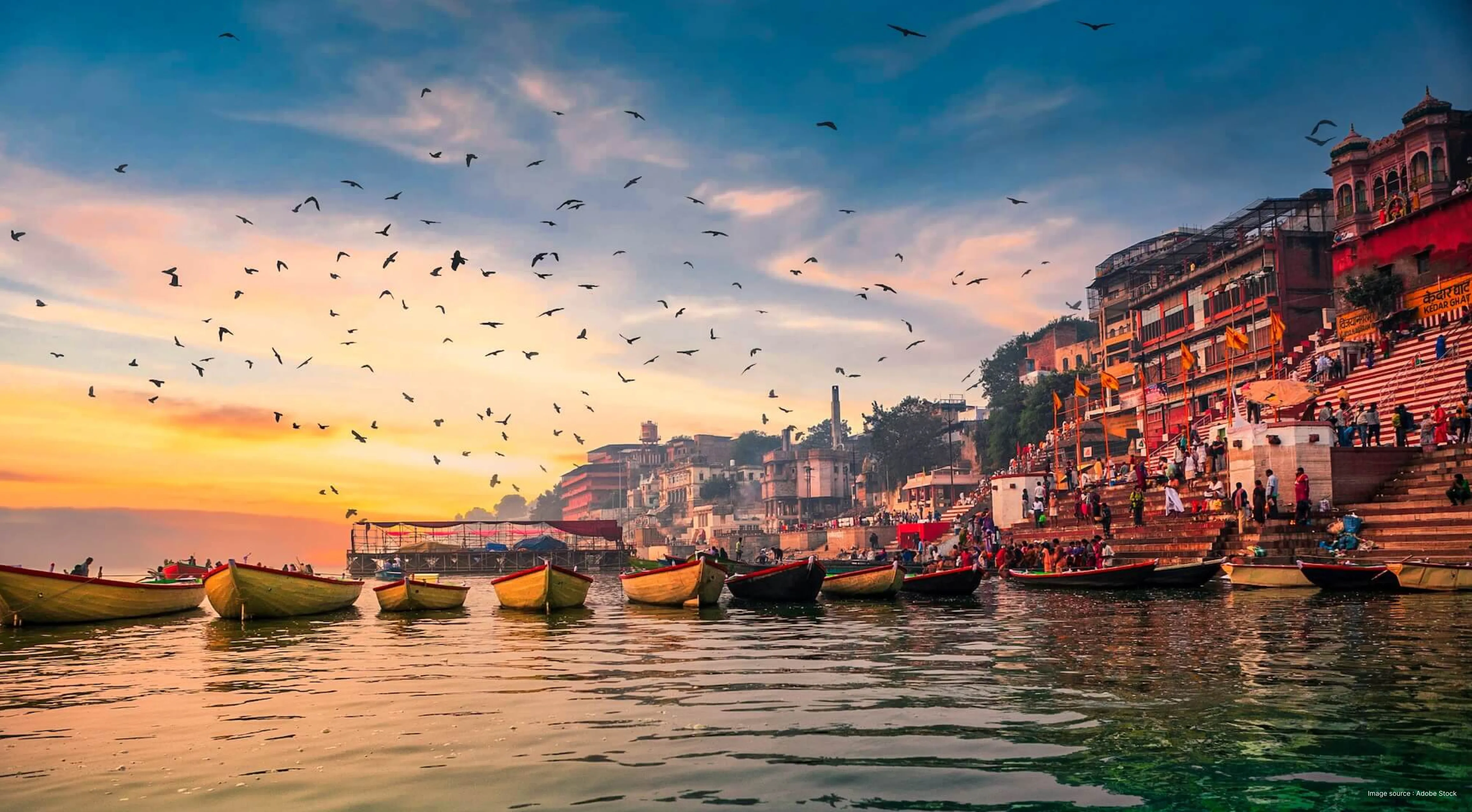 Morning boat ride at Assi Ghat Varanasi during sunrise with pilgrims and traditional wooden boats on the Ganges.