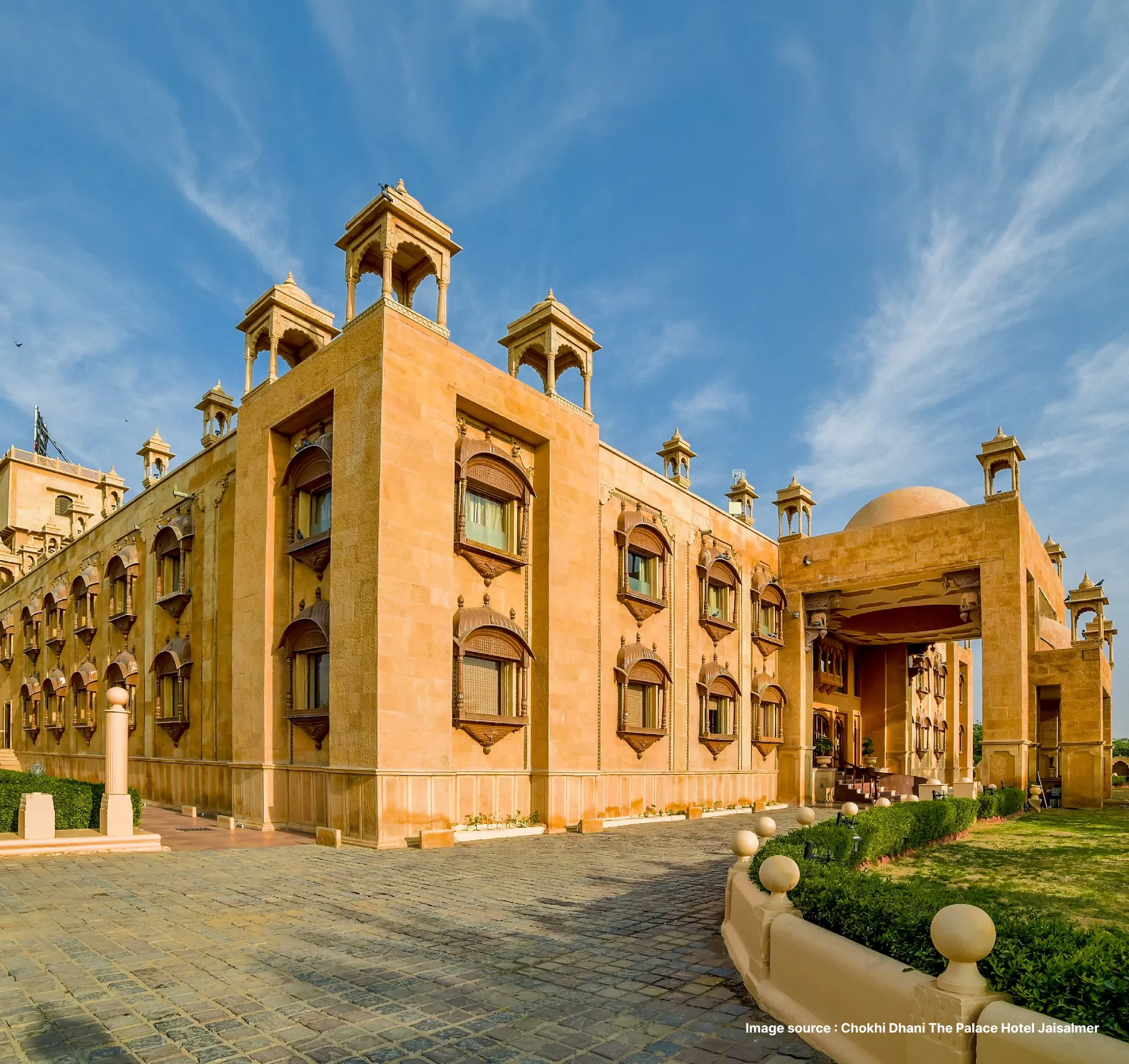 golden sandstone building of the chokhi dhani palace hotel of jaisalmer during daytime