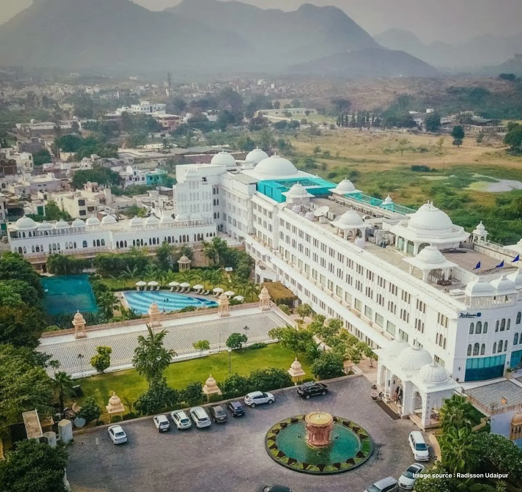 white traditional indian style building of the radisson hotel in an aerial shot with its pool and gardens