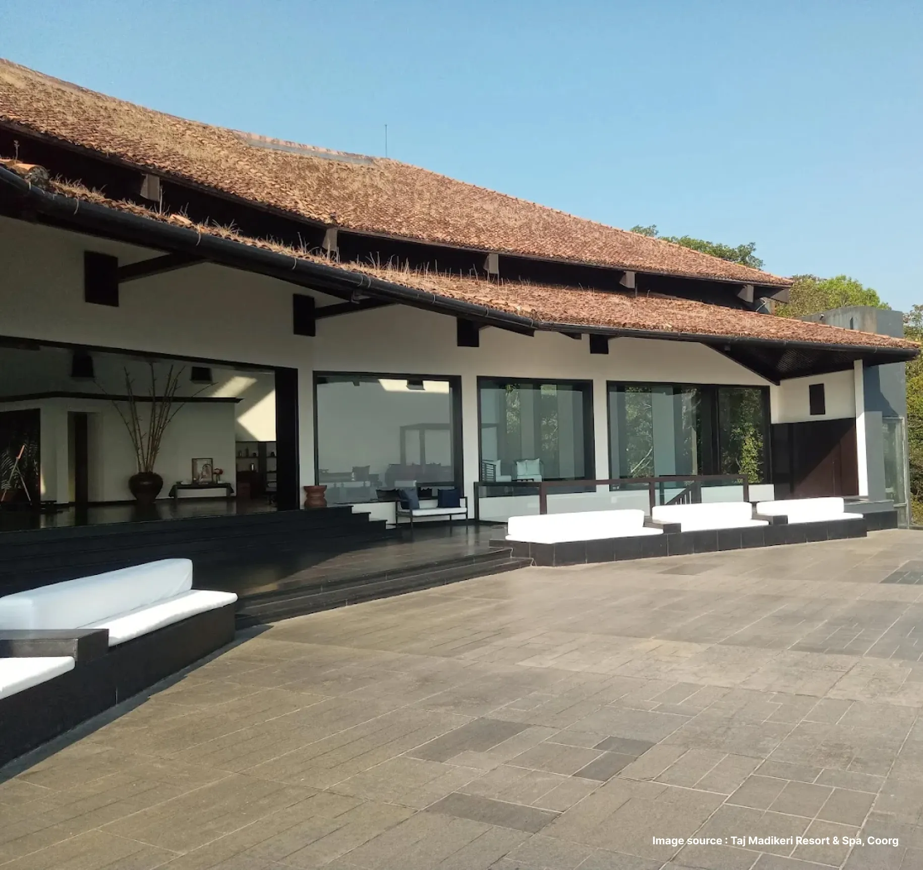 traditional cottage style villa suites with sofas outside on a sunny day of the taj madikeri resort